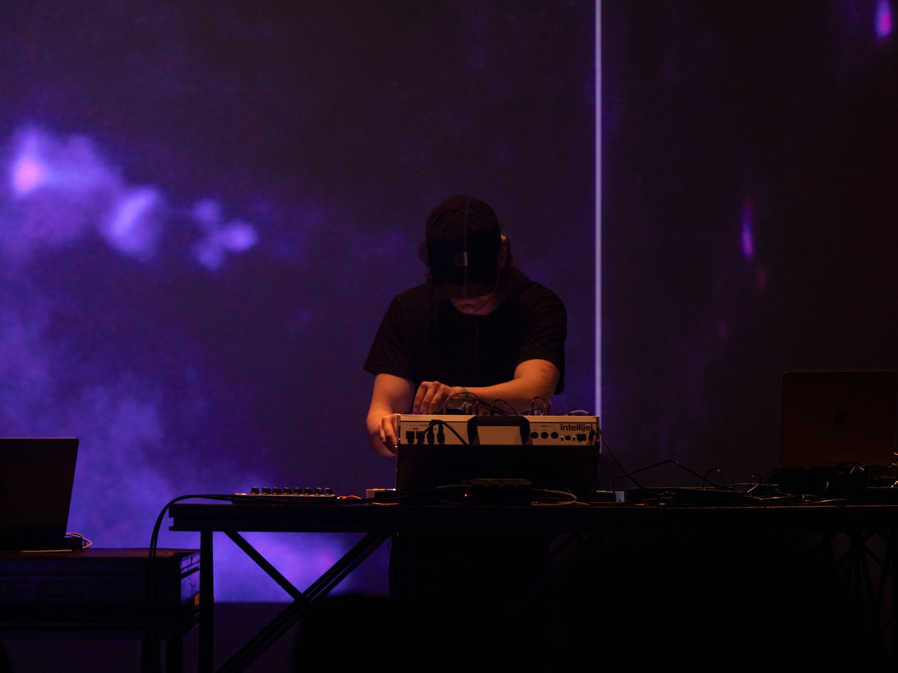 Løgømyx performing on modular synthesizer in front of violet projections